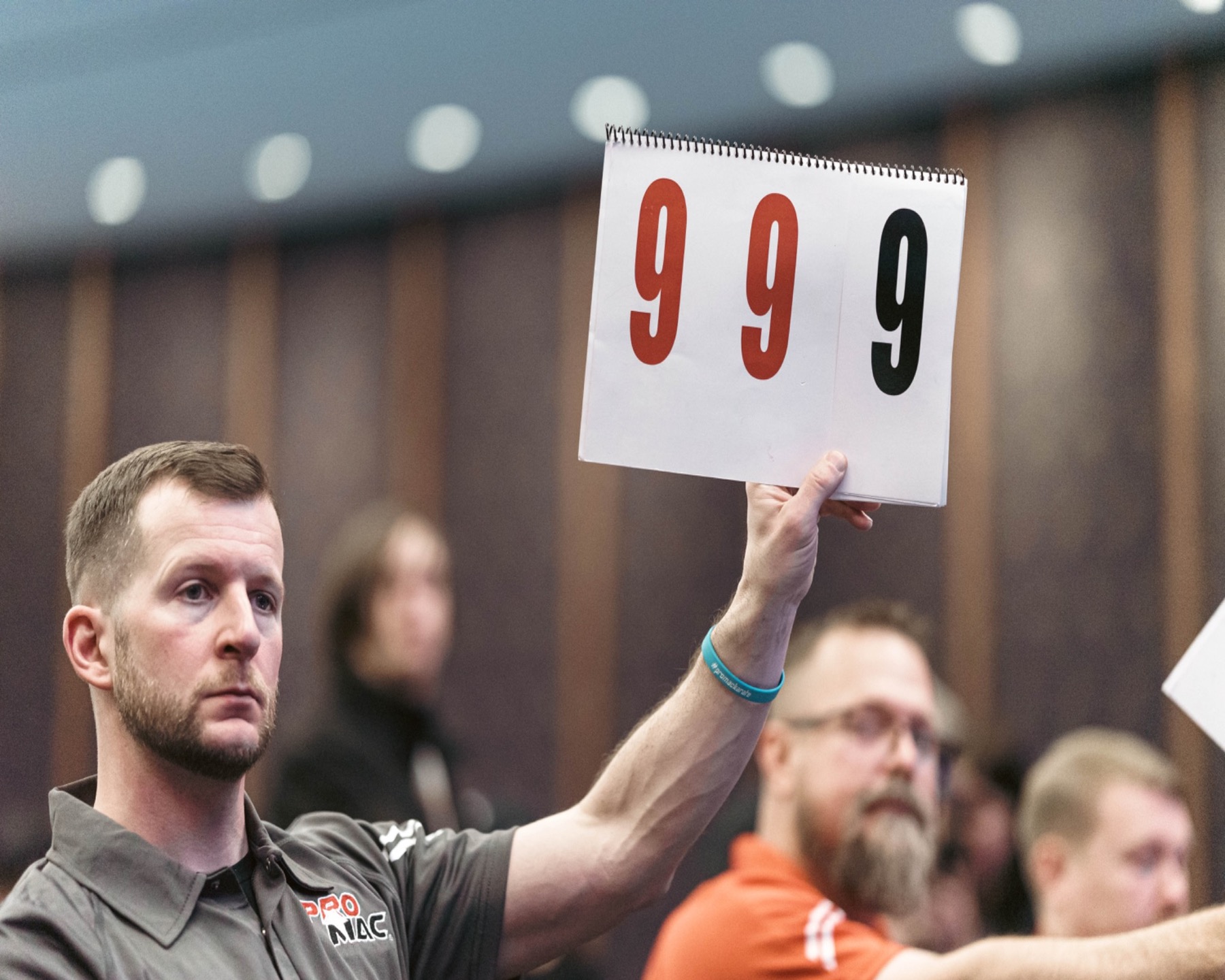 PROMAC official raising a 9.99 scorecard during competition